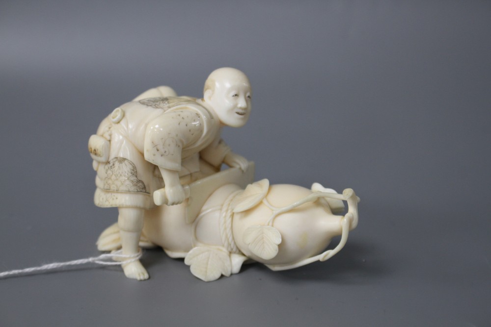 A Japanese Meiji period ivory okimono carved with a man carving a giant gourd, signed, length 10cm, height 7cm